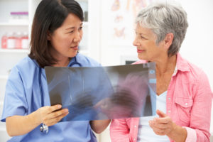 nurse looking at x-ray with senior woman