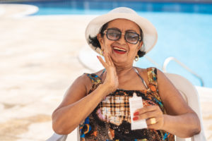 Senior woman applying suntan lotion