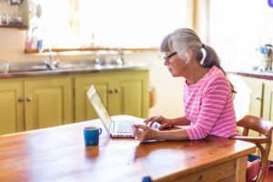 senior female browses online in her kitchen