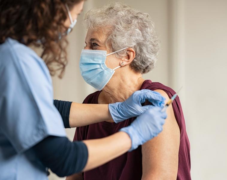 A nurse gives an elderly woman a vaccine shot.