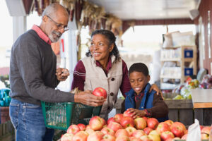 elderly man shopping for fruit with family