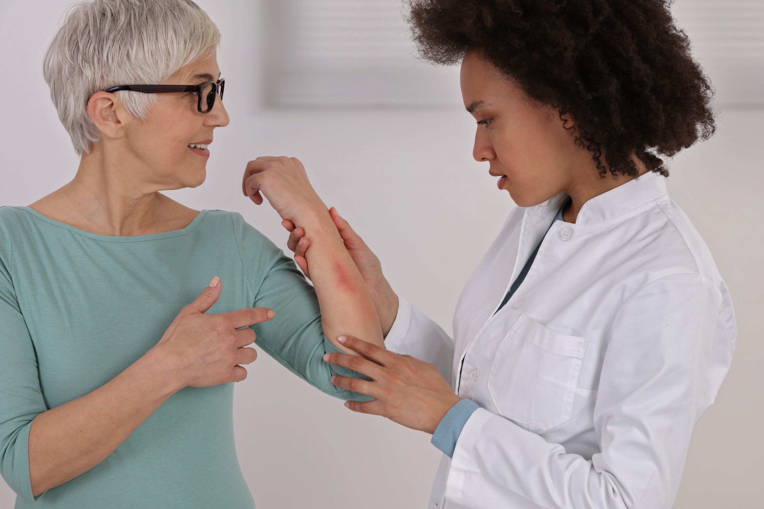 doctor looking at rash on elderly woman's arm