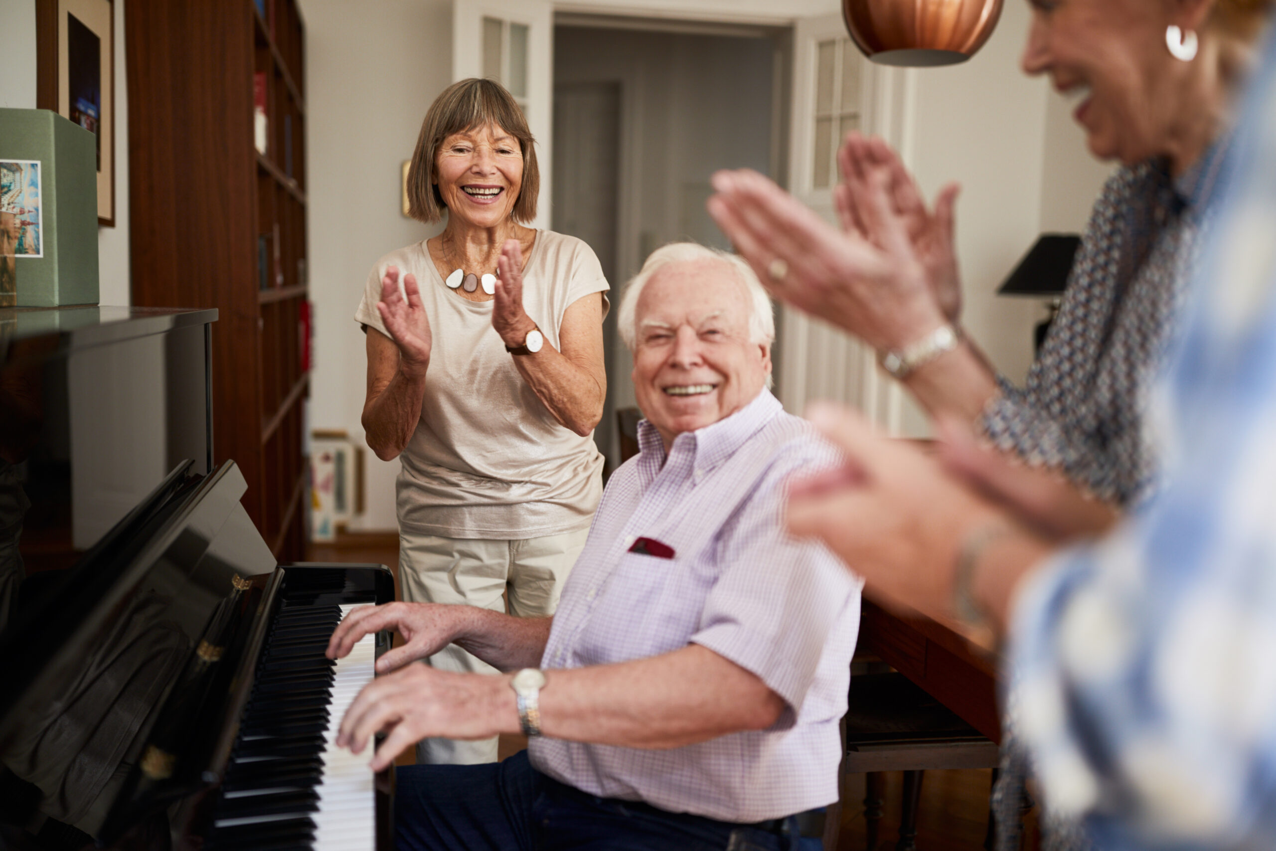 elderly man playing piano friends clapping