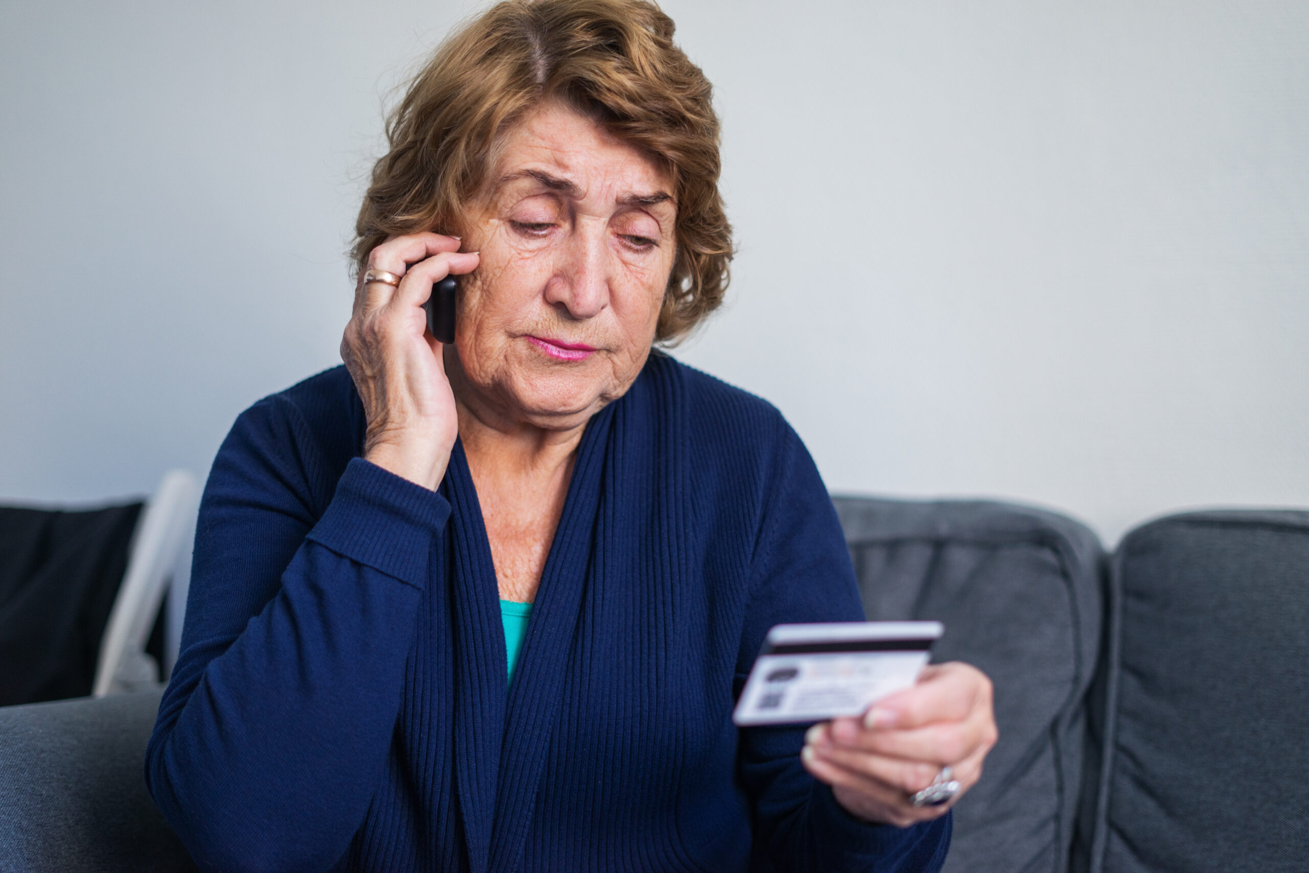 senior woman on the phone looking at credit card