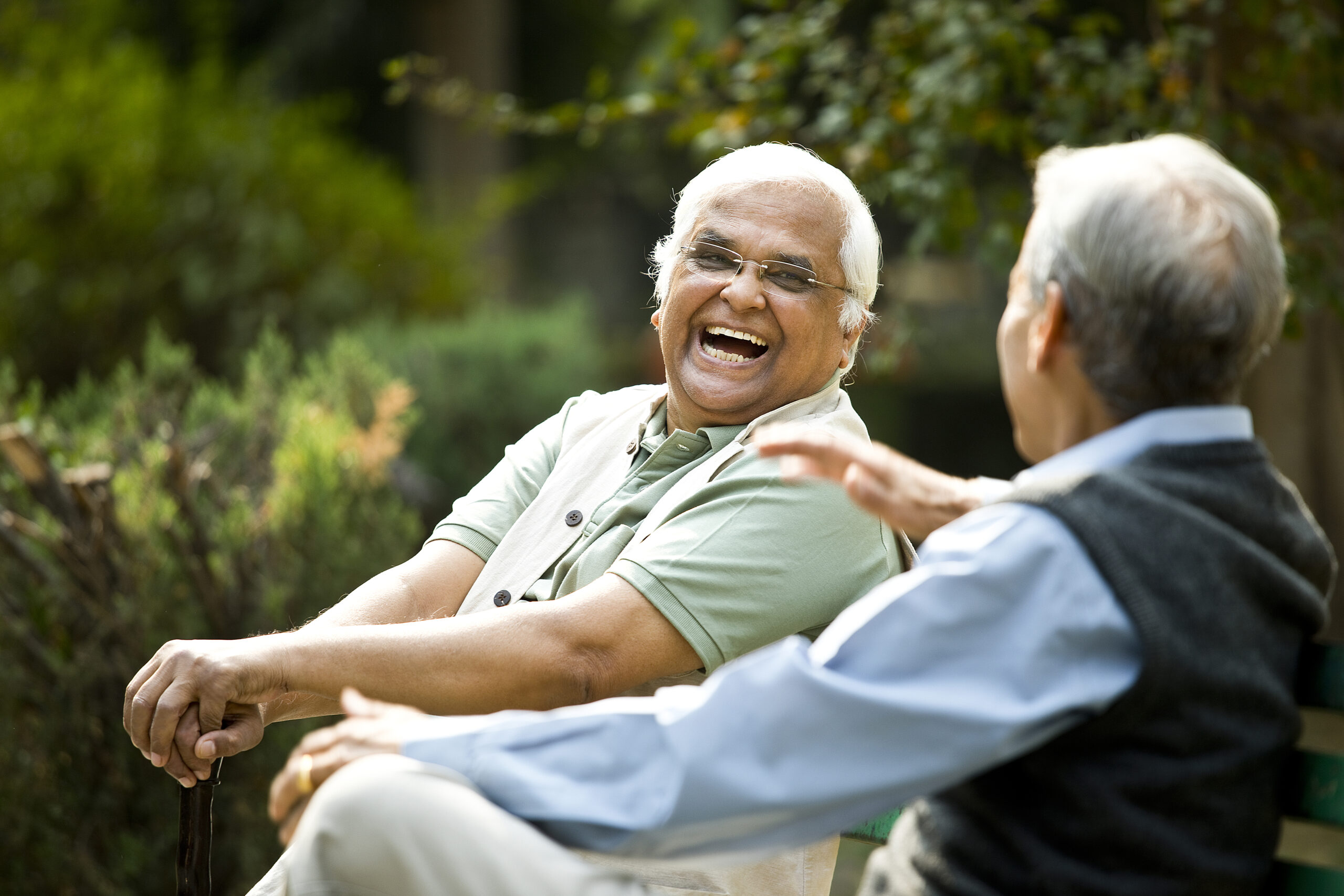two senior men laughing on bench