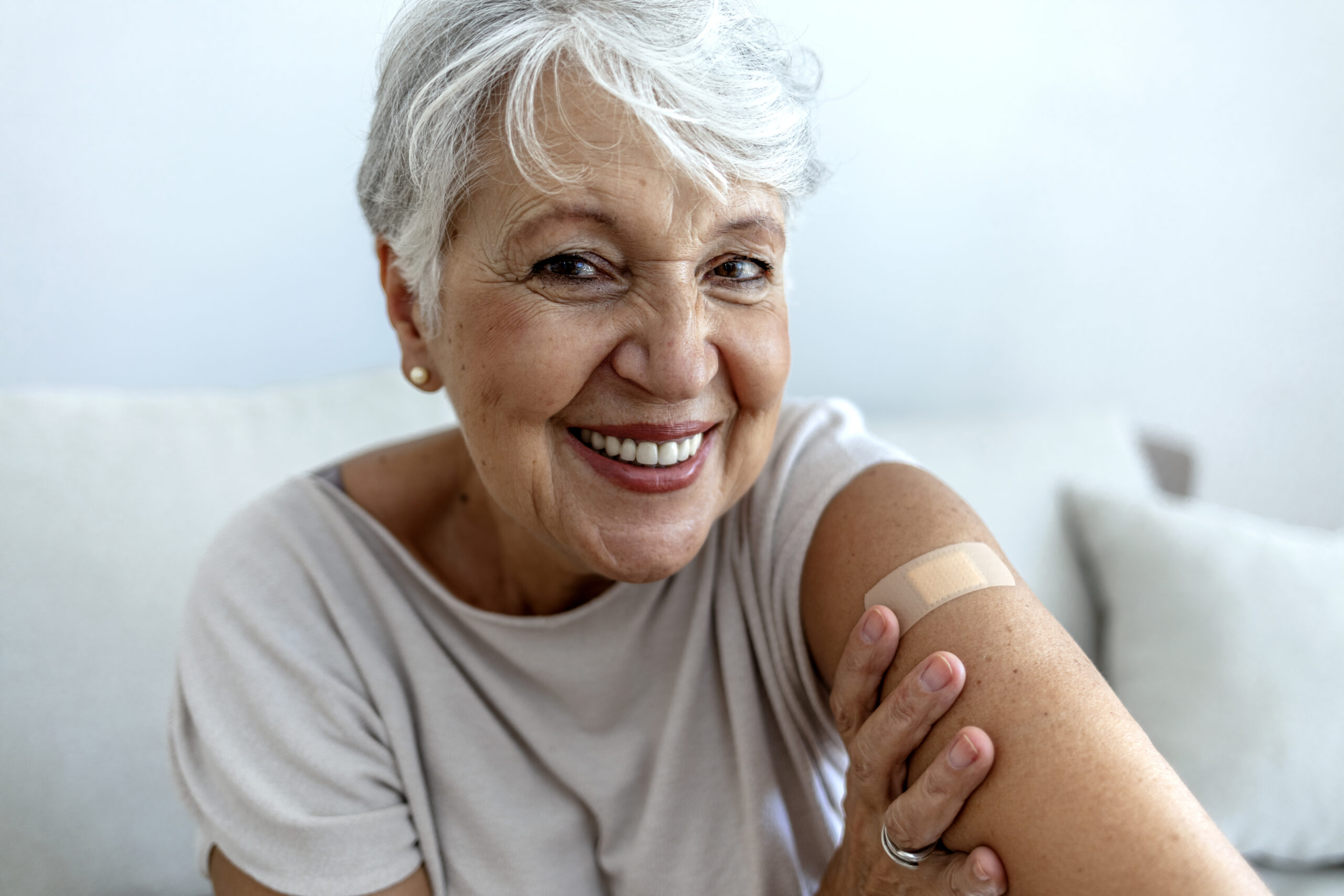 senior woman showing flu shot bandage