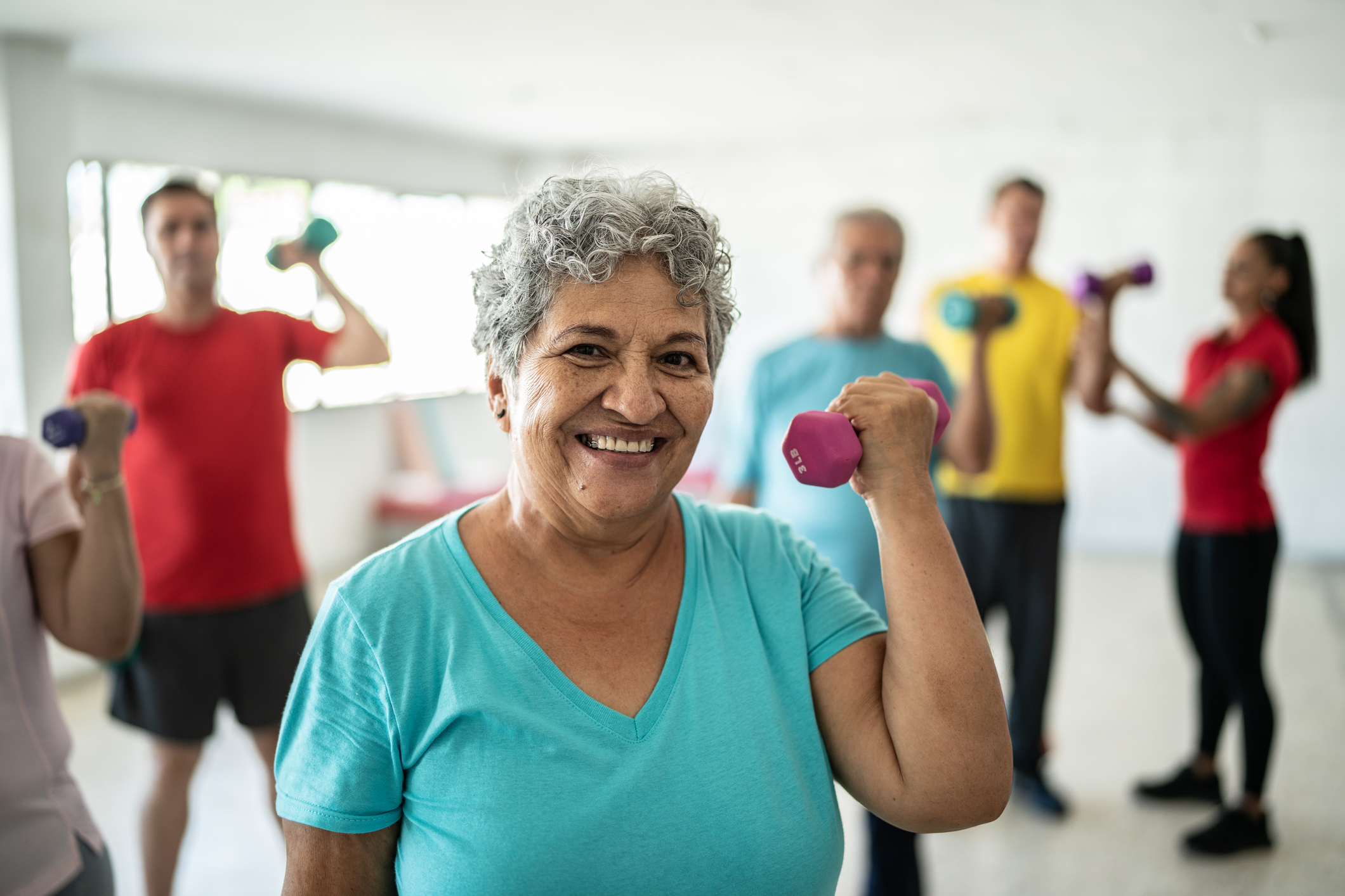 senior woman lifting weights in exercise class