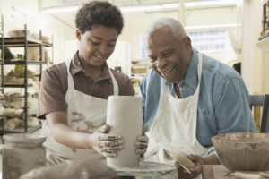 senior man doing pottery with grandson
